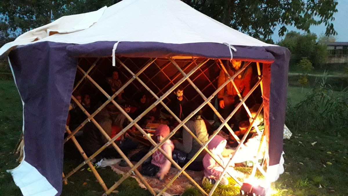 Grupo reunido junto a la FlexYurt iluminada de noche